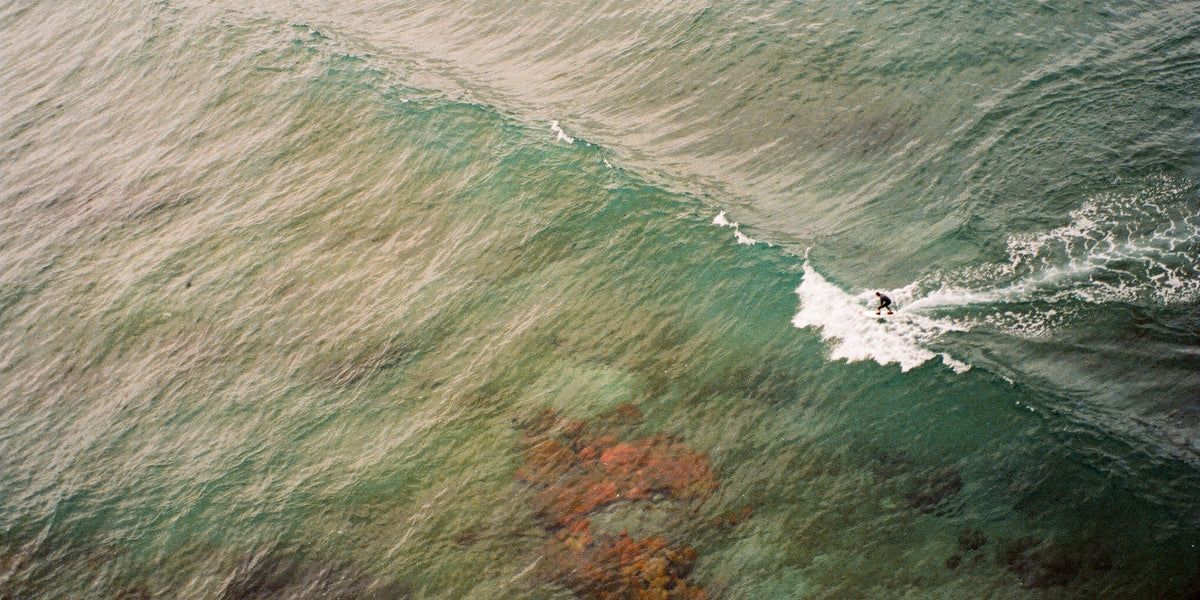 Aerial view of a surfer on a sea-green wave