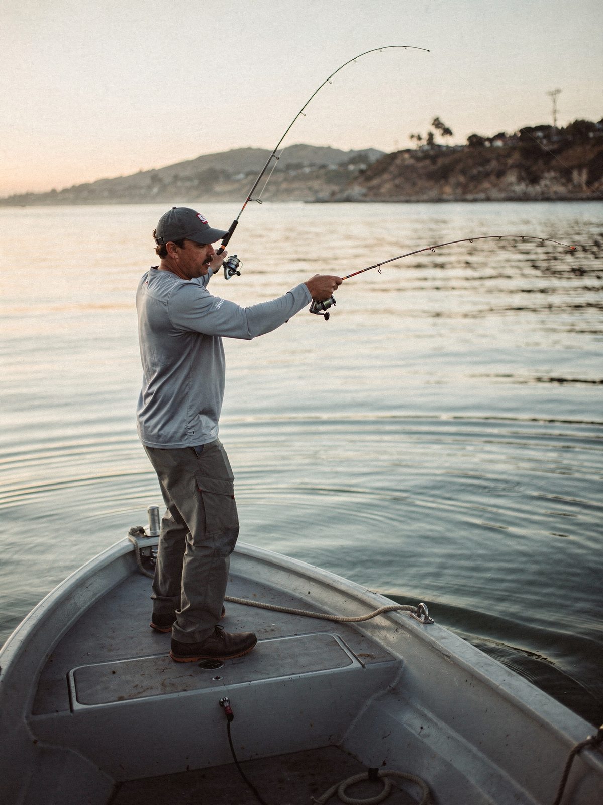 Angler casting from a skiff at sunrise