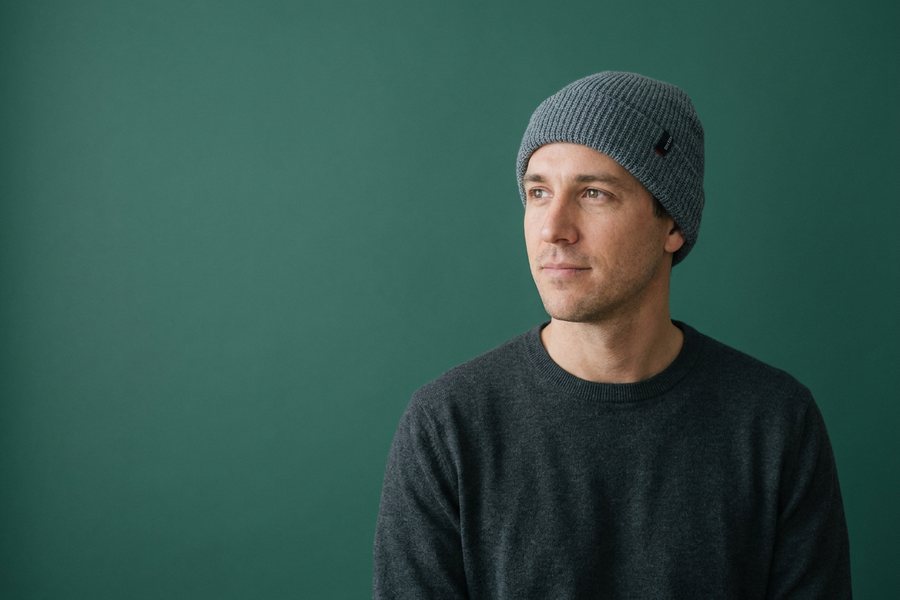 Man in a grey Brixton beanie against a sage green backdrop
